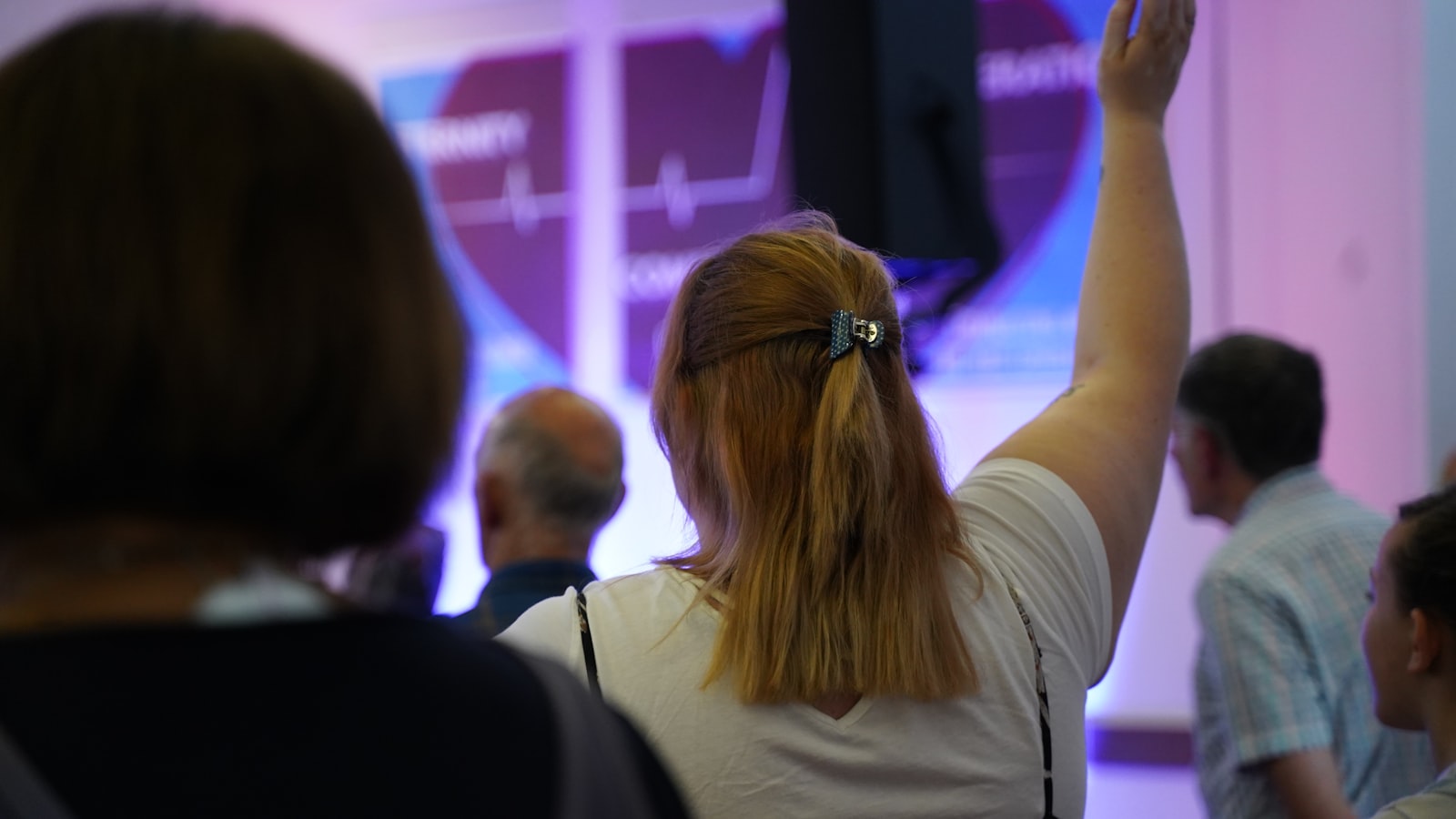 Church congregation worshiping with one person raising a hand